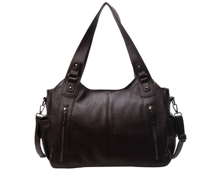 Black leather handbag with multiple zippers on a white background
