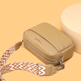 Beige crossbody bag with a patterned strap on a beige background