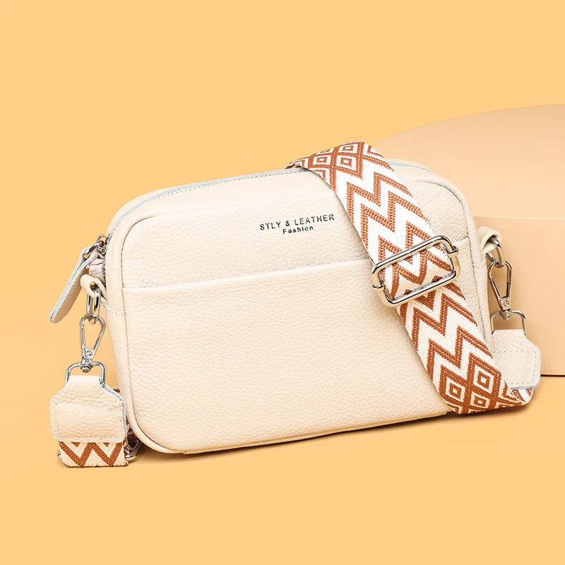 Cream-colored handbag with a patterned strap on a beige background