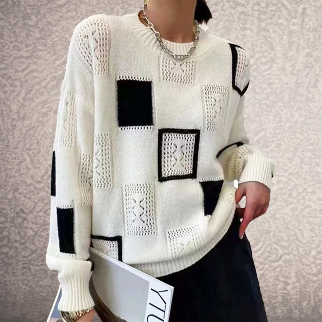 Person wearing a white sweater with black square patterns against a neutral background