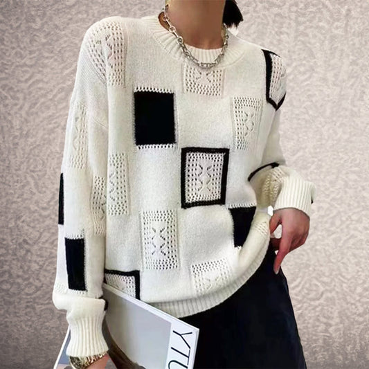 Person wearing a white sweater with black square patterns against a neutral background
