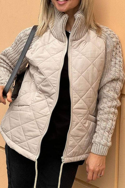 Person wearing a beige quilted vest over a knitted sweater with a neutral background