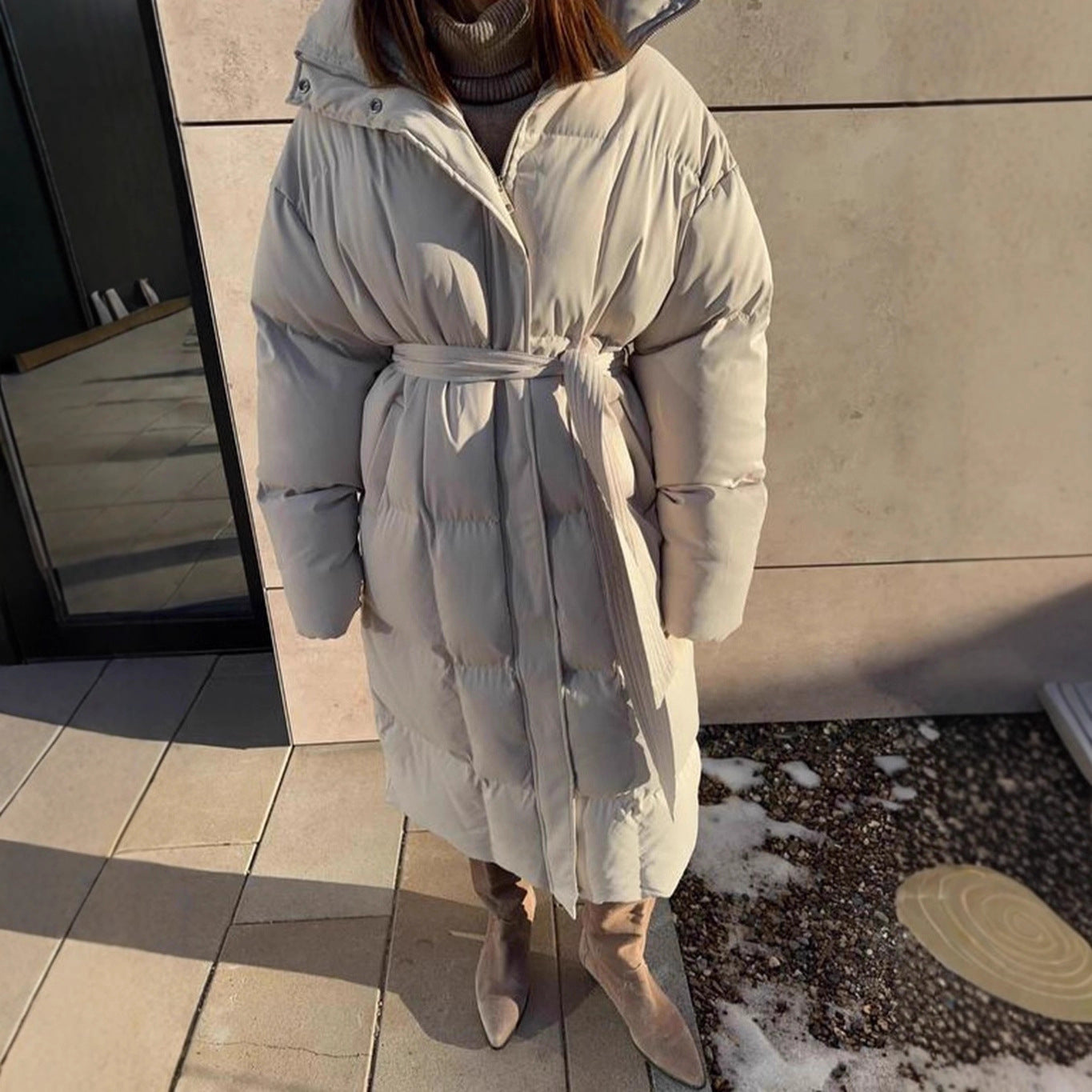 Person wearing a light gray puffer coat standing outdoors on a snowy day.