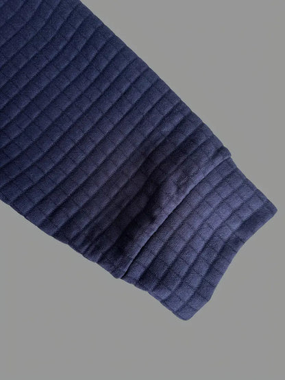 Navy blue ribbed knit sweater sleeve on a gray background