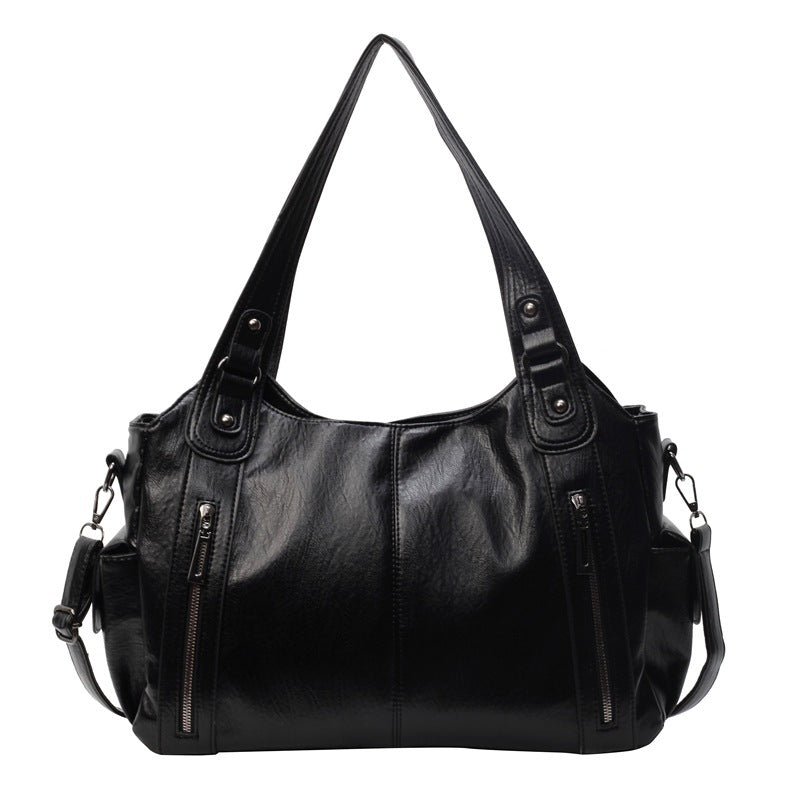 Black leather handbag with multiple pockets and zippers on a white background