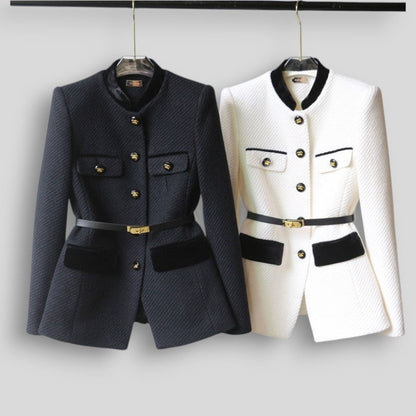 Two jackets, one black and one white, on hangers against a plain background.