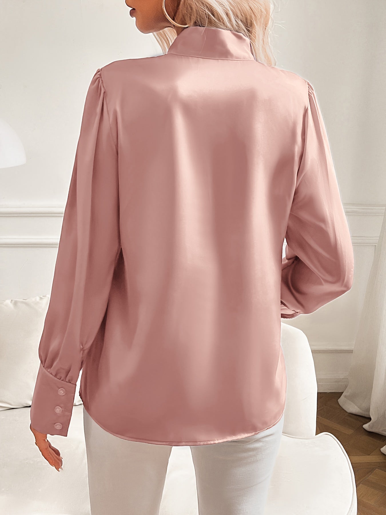 Pink satin blouse worn by a person in a minimal indoor setting