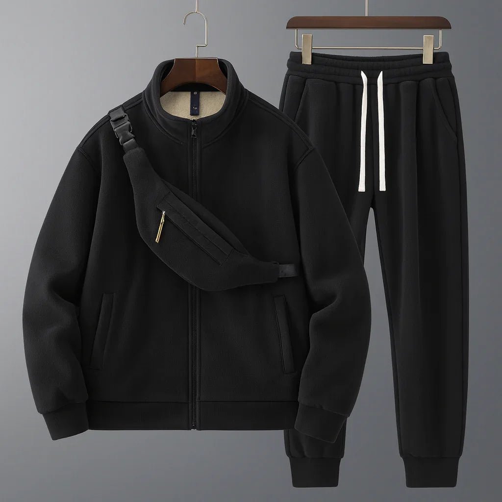Black tracksuit with jacket and pants on hangers against a gray background