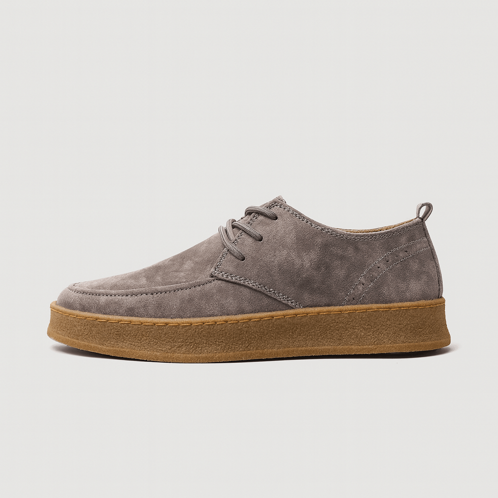 Gray suede shoe with brown sole on a light gray background