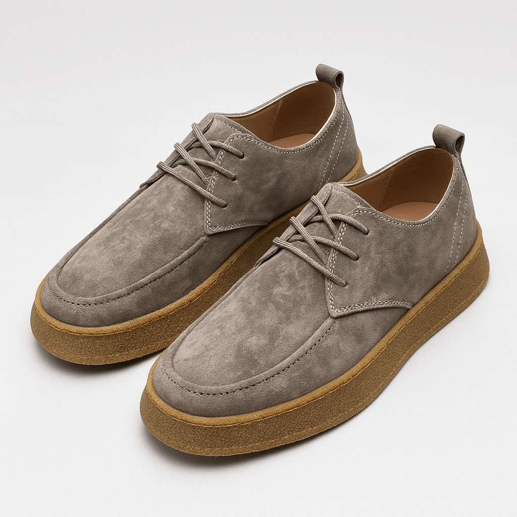 Pair of gray suede shoes with brown soles on a white background