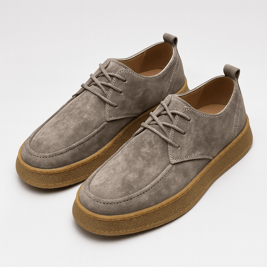 Pair of gray suede shoes with brown soles on a white background