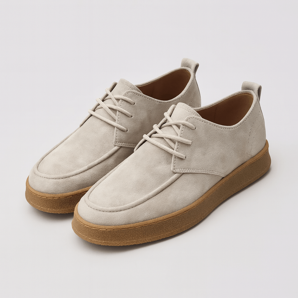 Pair of beige suede shoes with brown soles on a light gray background