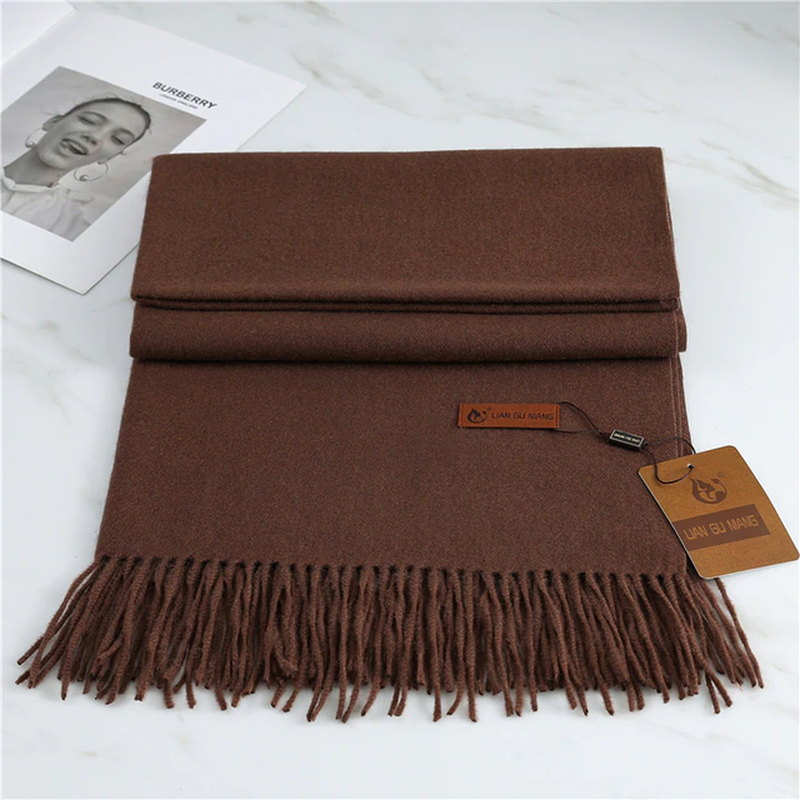Brown scarf with fringes and a brand tag on a white surface