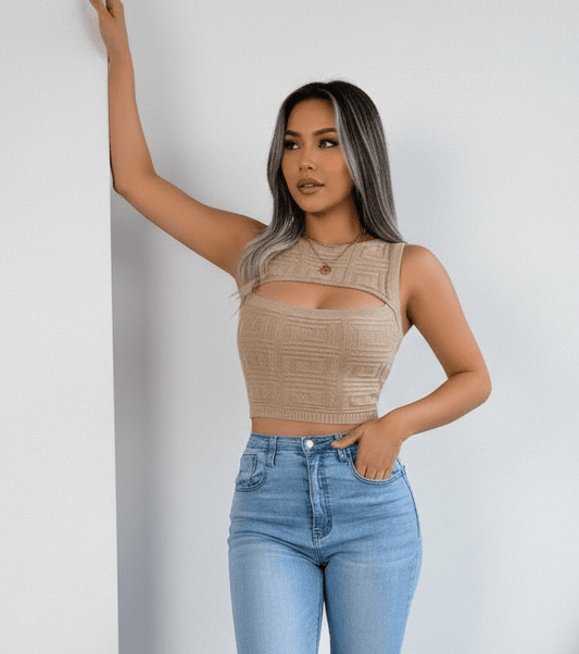 Woman wearing a beige sleeveless top and blue jeans against a plain background