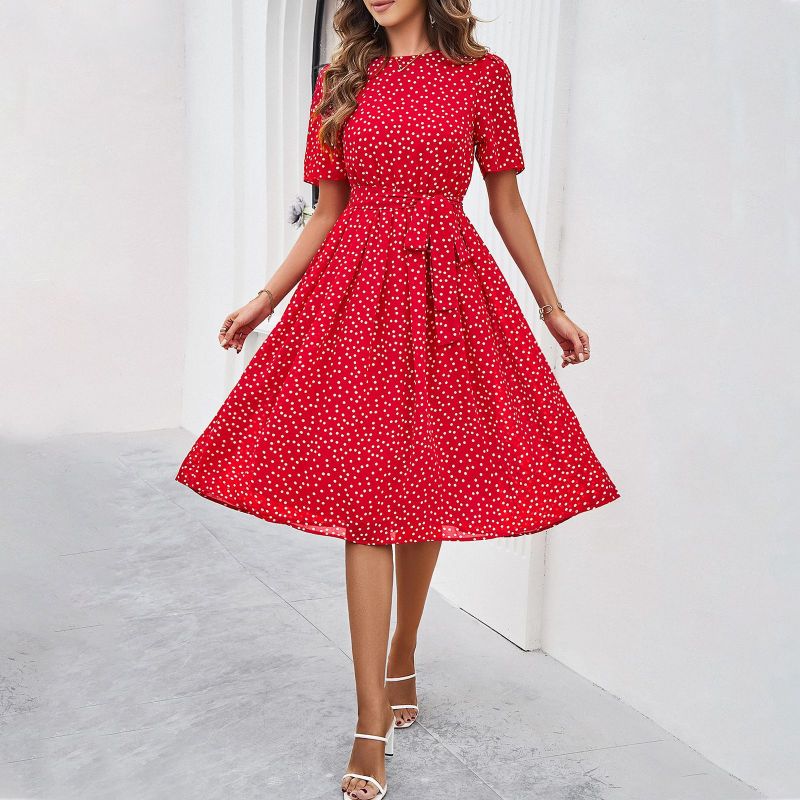 Woman wearing a red polka dot dress against a white background