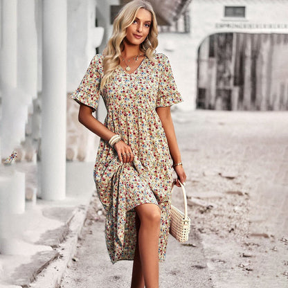 Woman in a floral dress holding a bag on a street.