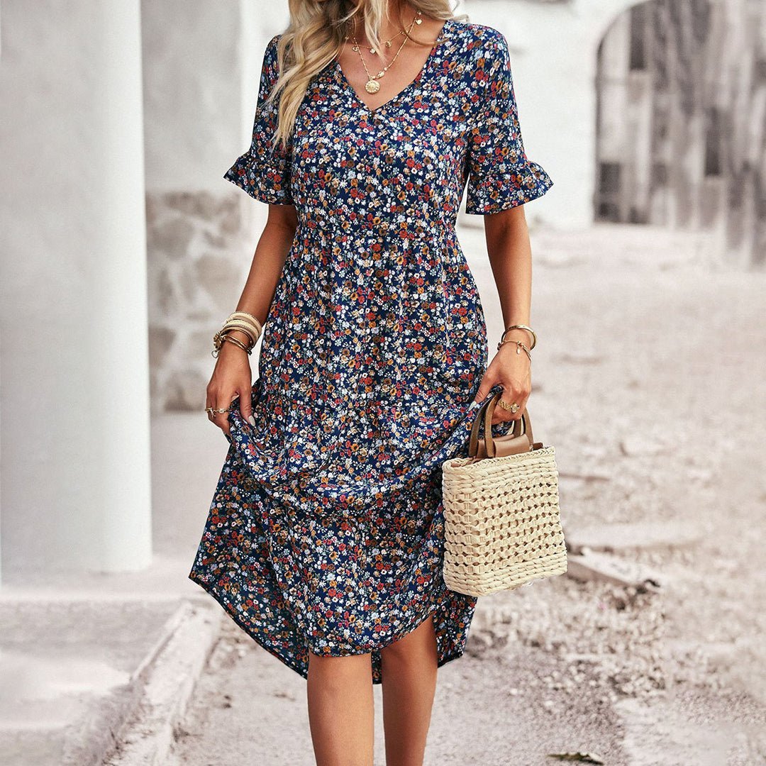 Woman wearing a floral dress holding a straw bag on a street.
