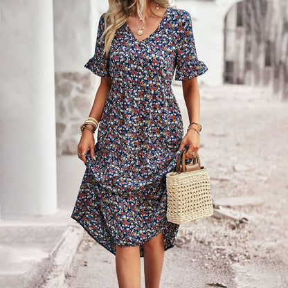 Woman wearing a floral dress holding a straw bag on a street.