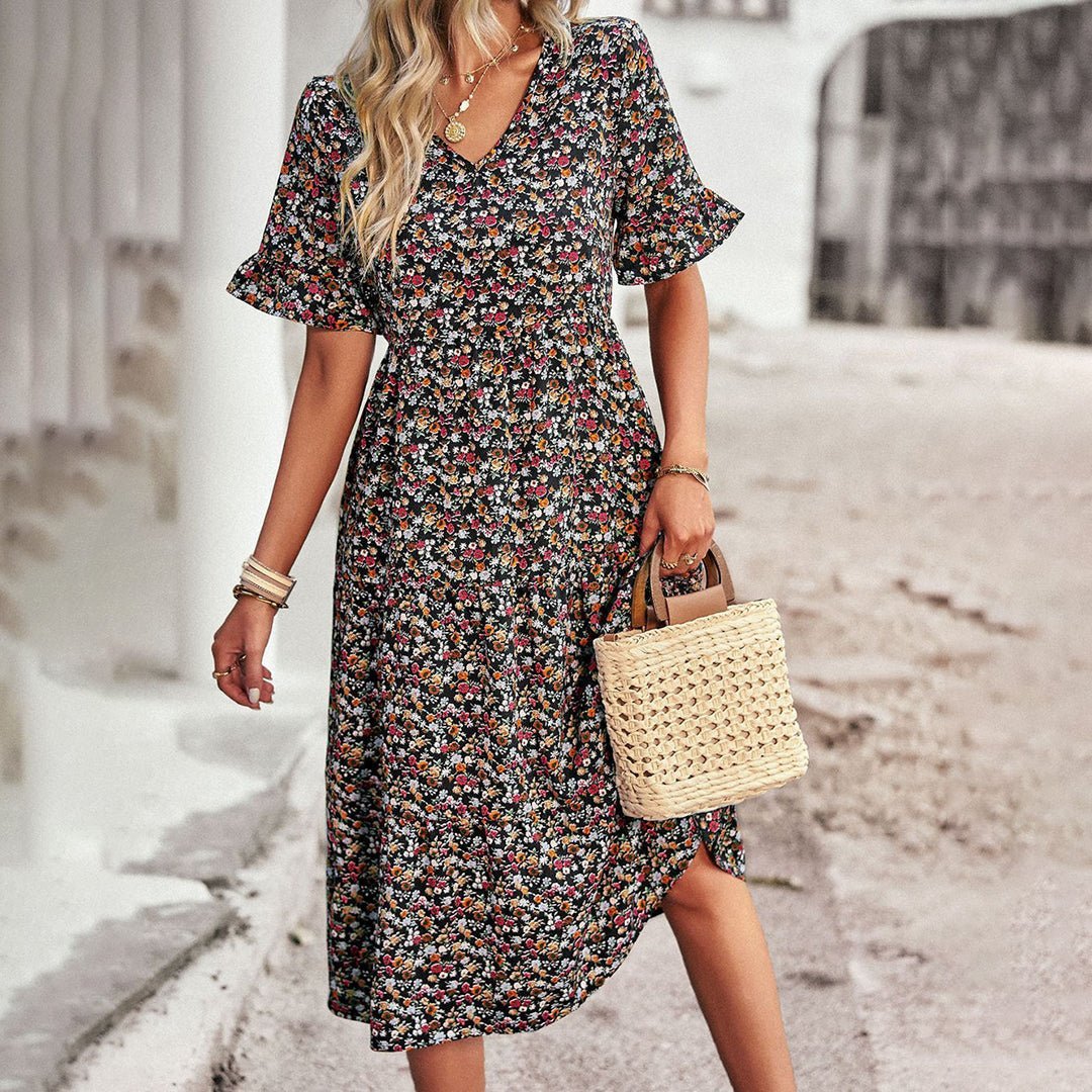 Woman wearing a floral dress holding a straw bag on a street.