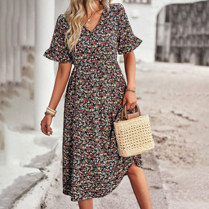 Woman wearing a floral dress holding a straw bag on a street.