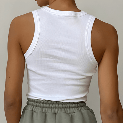 Person wearing a white tank top and green pants against a neutral background