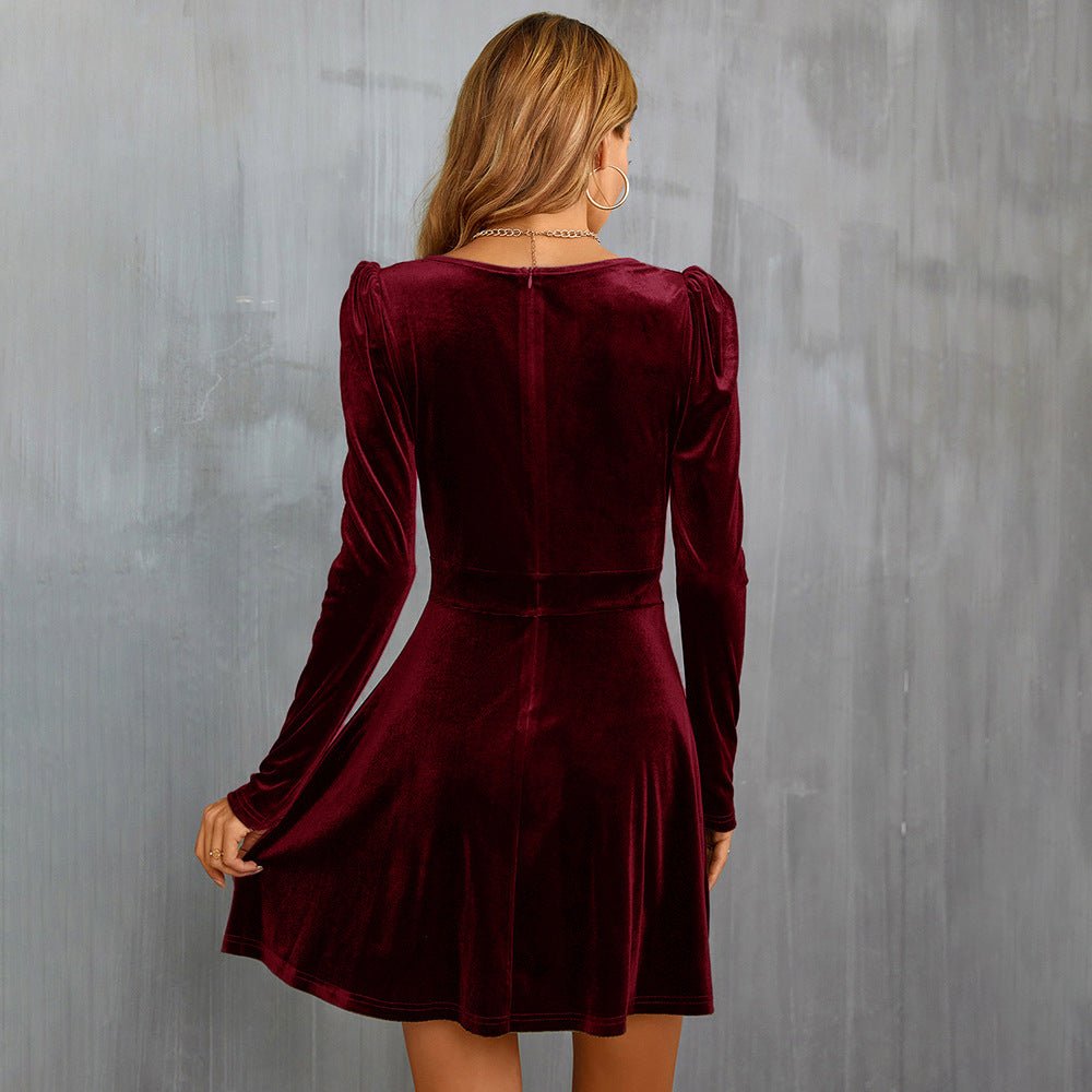 Woman wearing a burgundy velvet dress against a gray wall