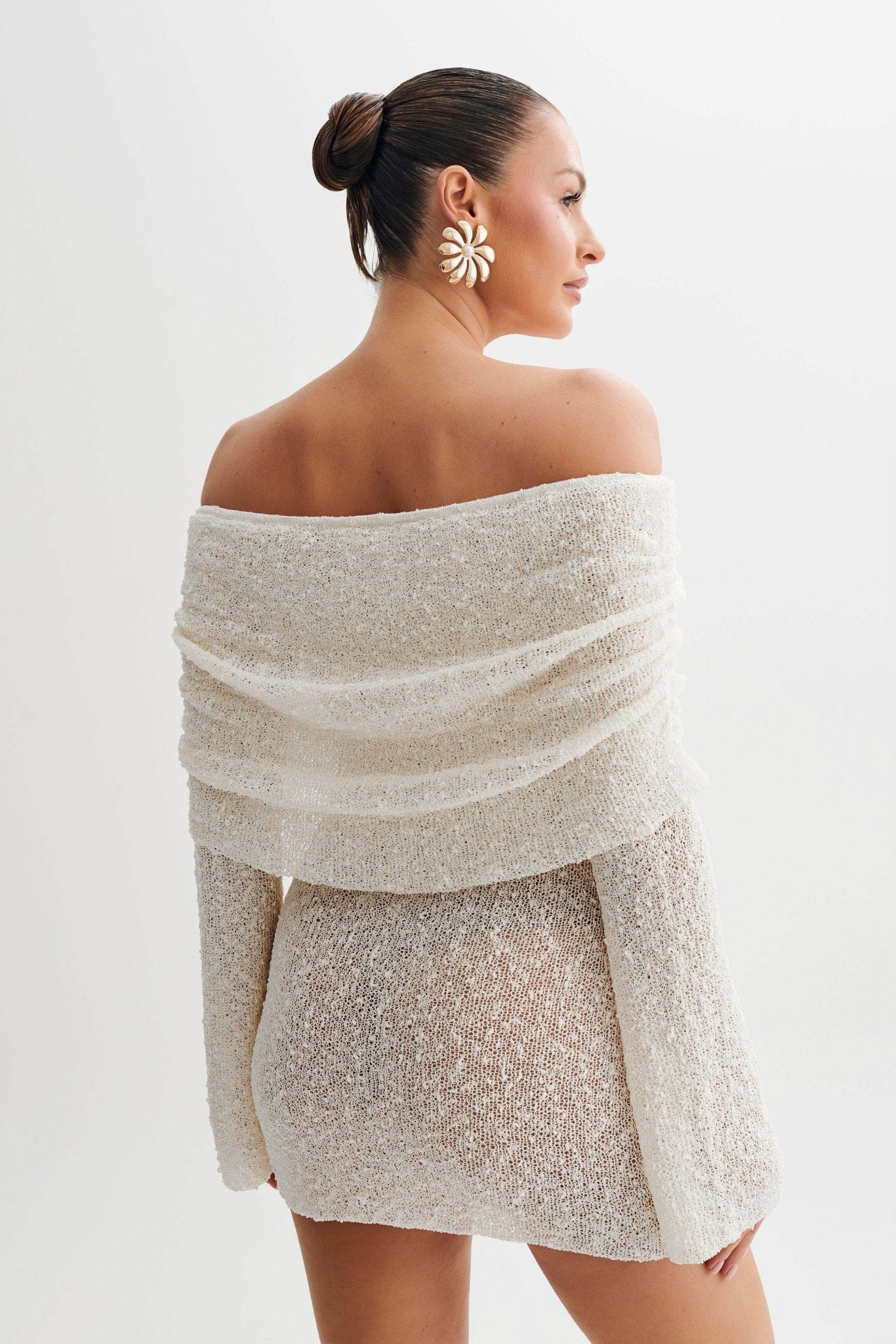 Woman wearing a sparkling off-shoulder top and skirt set on a white background