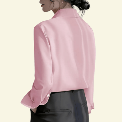 Person wearing a pink blouse with rolled-up sleeves on a beige background
