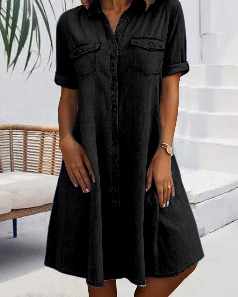 Person wearing a black button-up dress standing in an outdoor setting.