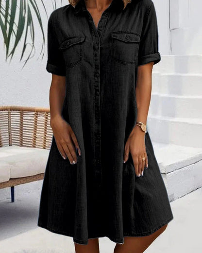Person wearing a black button-up dress standing in an outdoor setting.