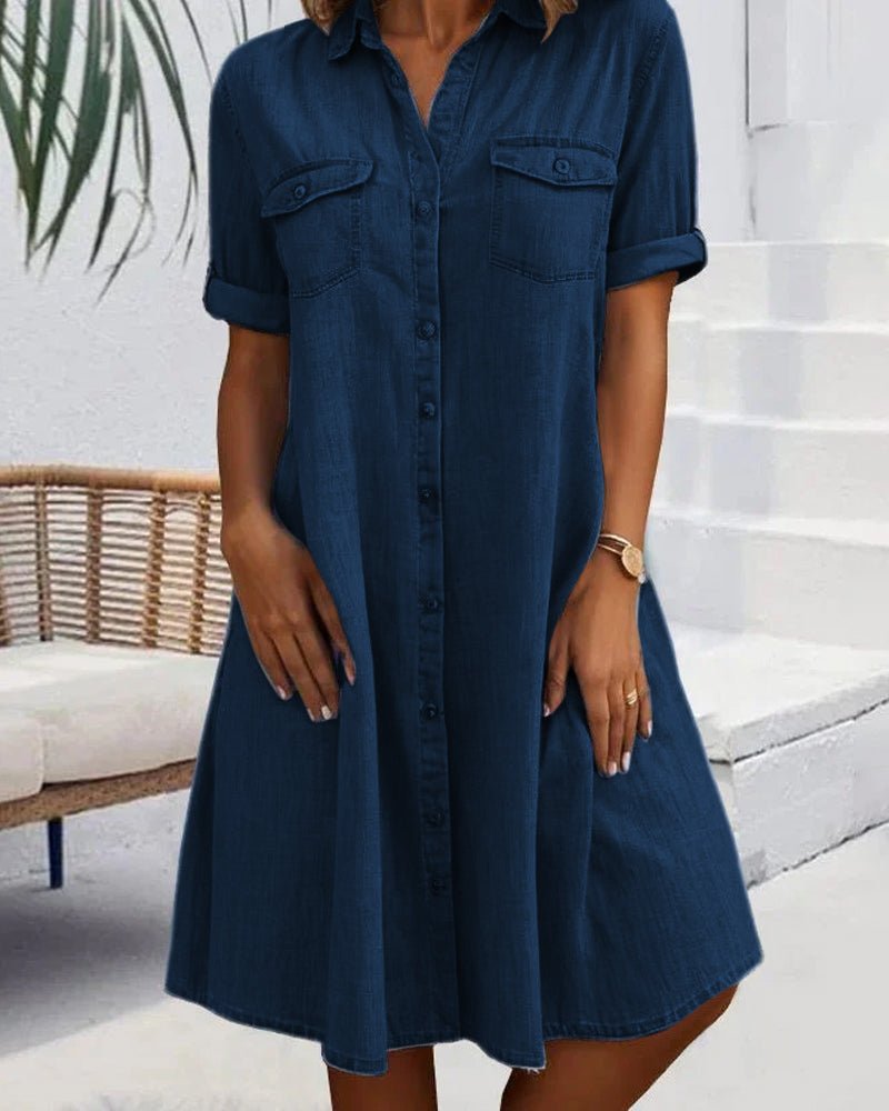Woman wearing a blue denim dress standing on a white staircase.