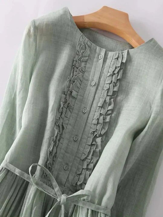 Green dress with intricate detailing on a hanger against a white background