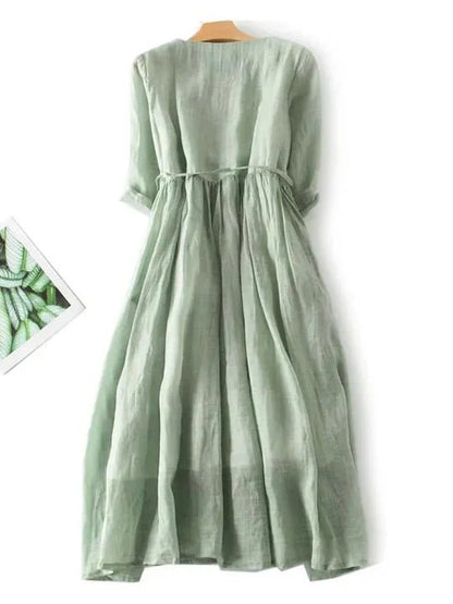 Green dress on a wooden hanger against a white background