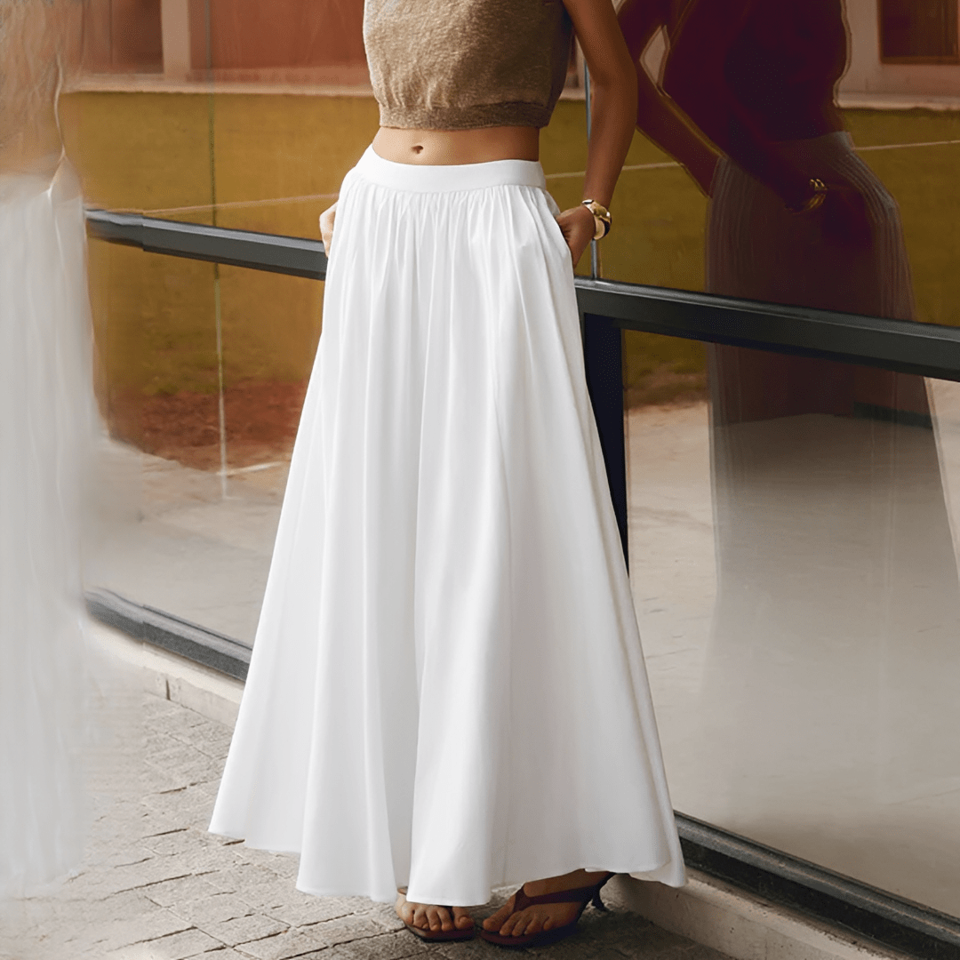Person wearing a white skirt standing near a reflective surface.