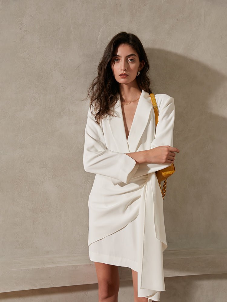 Woman wearing a white blazer dress against a beige wall