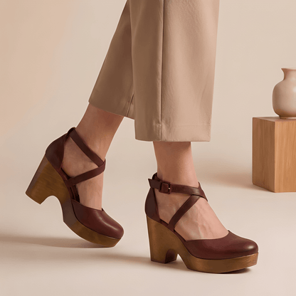 Brown platform shoes worn with beige pants on a neutral background