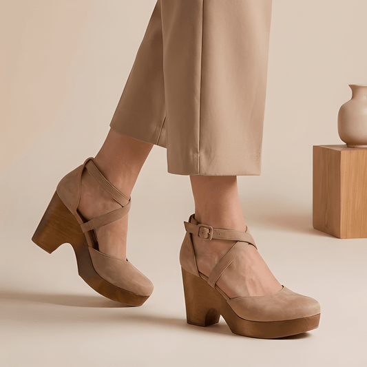 Beige suede platform shoes worn with beige pants on a neutral background