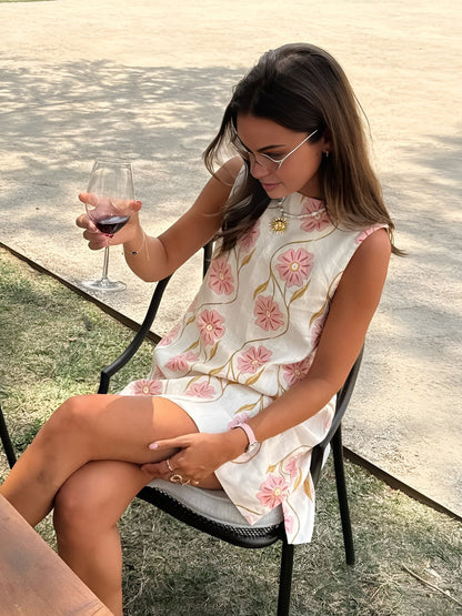 Woman in a floral dress holding a glass of red wine outdoors.