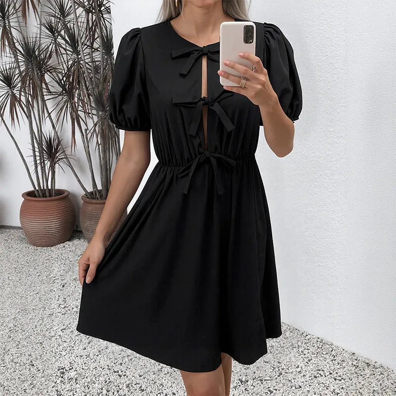 Person wearing a black dress taking a mirror selfie indoors.