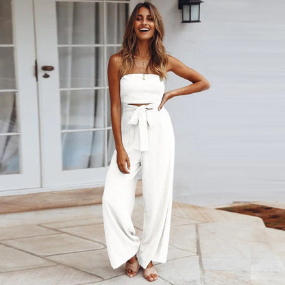 Woman wearing a white strapless top and wide-leg pants standing on a patio.