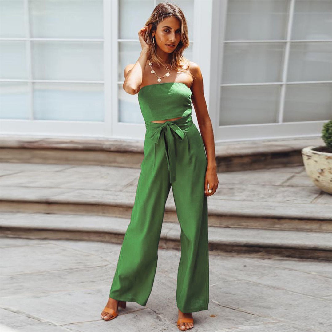 Woman wearing a green strapless jumpsuit standing on a wooden deck.