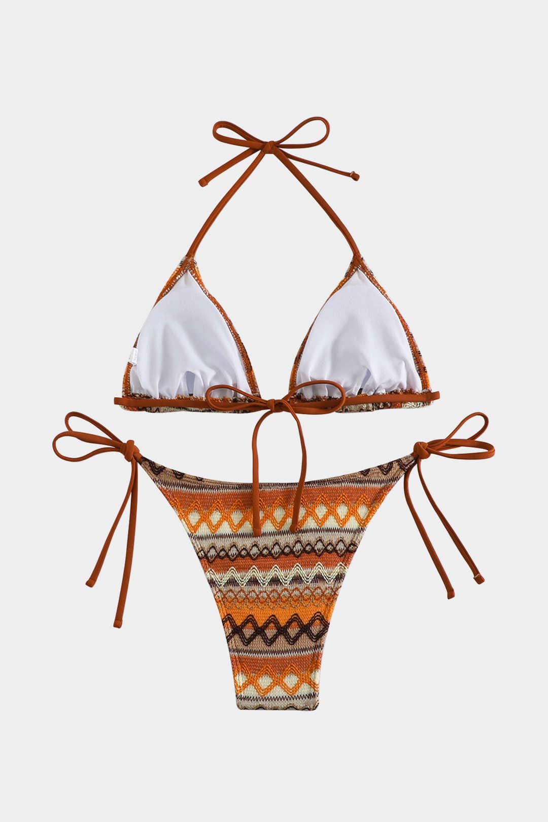 Bikini set with white top and patterned orange bottom on a light gray background