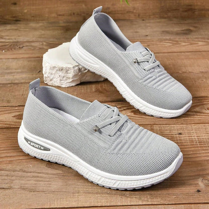 Gray sneakers with white soles on a wooden surface