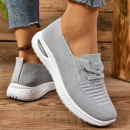 Gray sneakers with white soles on a wooden floor