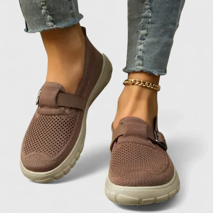 Brown slip-on shoes worn with light blue jeans on a white background