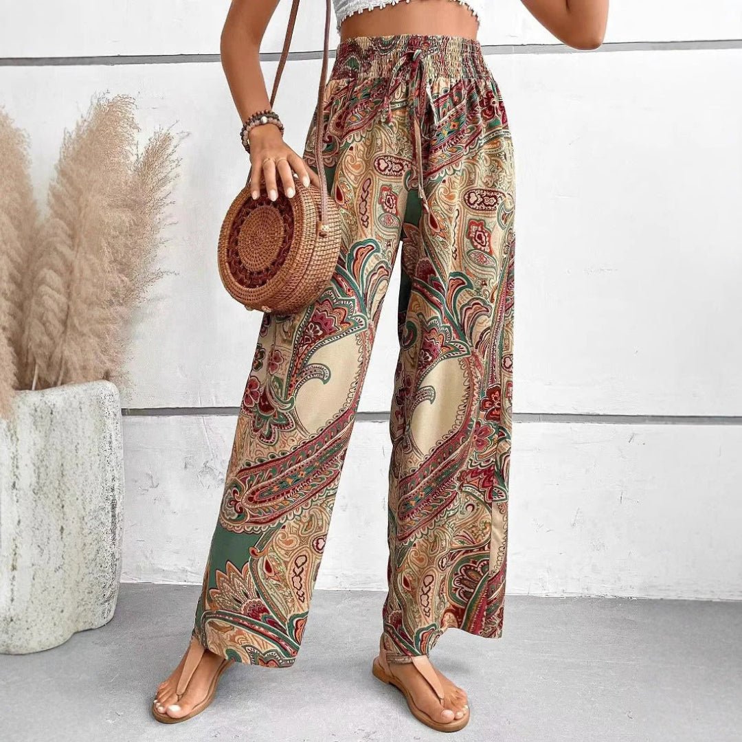 Person wearing patterned pants holding a round woven bag indoors.