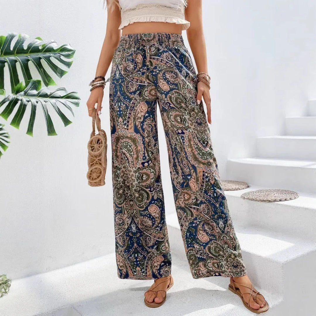 Person wearing patterned pants standing on a white staircase with greenery in the background