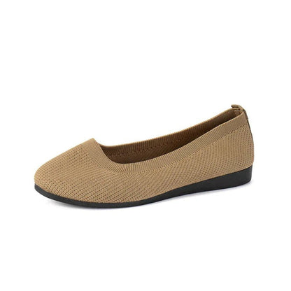 Beige flat shoe with black sole on a white background