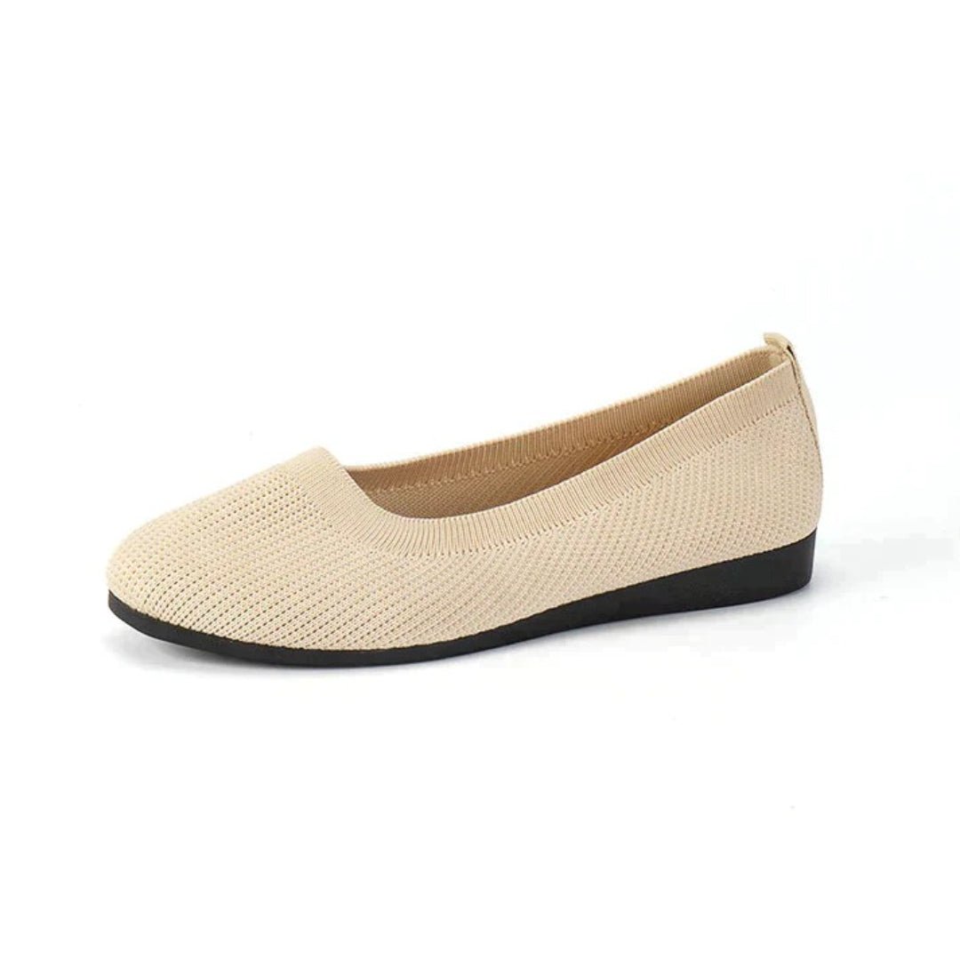 Beige flat shoe with black sole on a white background