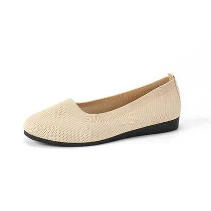 Beige flat shoe with black sole on a white background